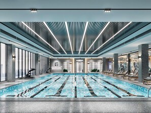 A modern indoor swimming pool with a clear view of the cityscape through large windows. - Pullman Linyi Lushang (Linyi)