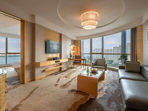 A modern living room with a large TV, a sofa, a coffee table, and a view of the city. - Pullman Linyi Lushang (Linyi)