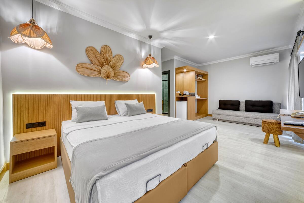 A modern bedroom with a large bed, bedside tables, a sofa, and a small seating area.