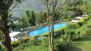 Une piscine entourée d’une végétation luxuriante, avec vue sur un lac.