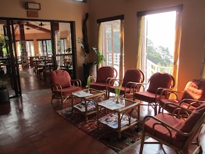 Relax in a spacious lounge area with wicker chairs, wooden tables, and a cozy rug.