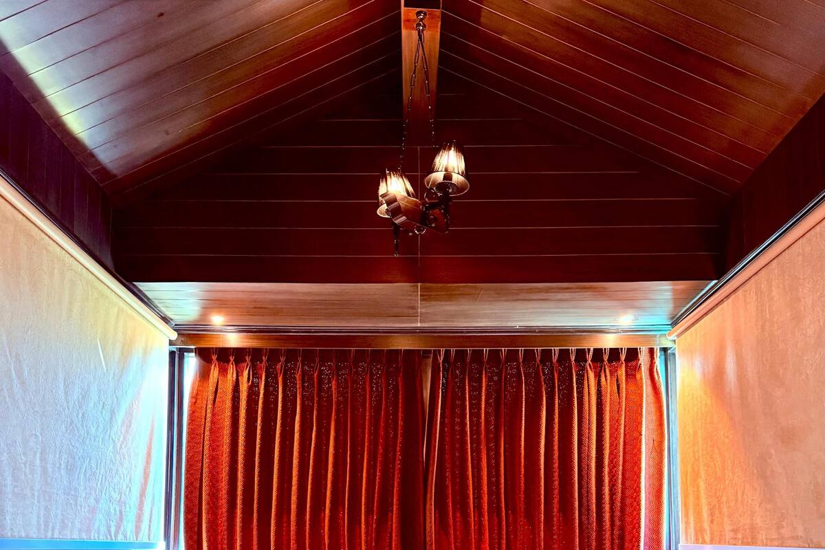 A large bed with red and white bedding, a wooden ceiling, and red curtains.