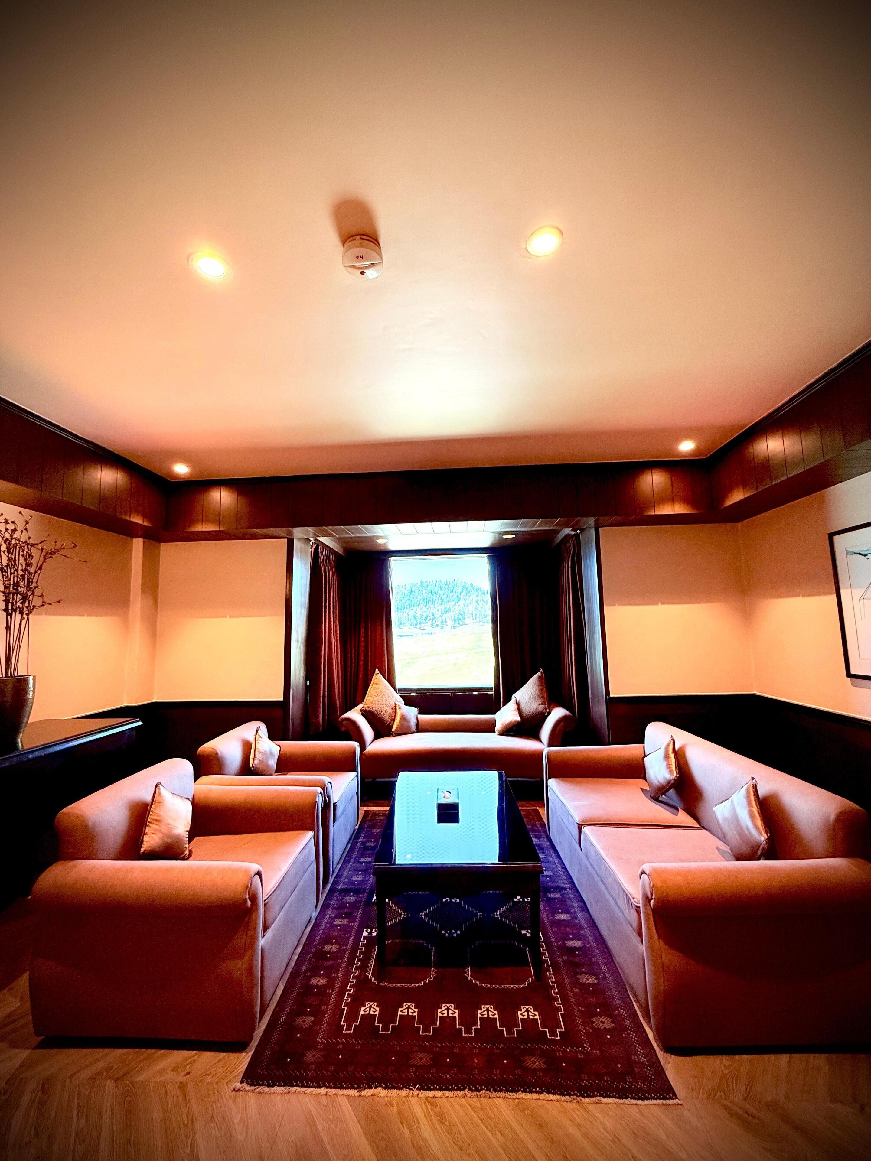 A modern living room with leather sofas, a central coffee table, and a large window with curtains.