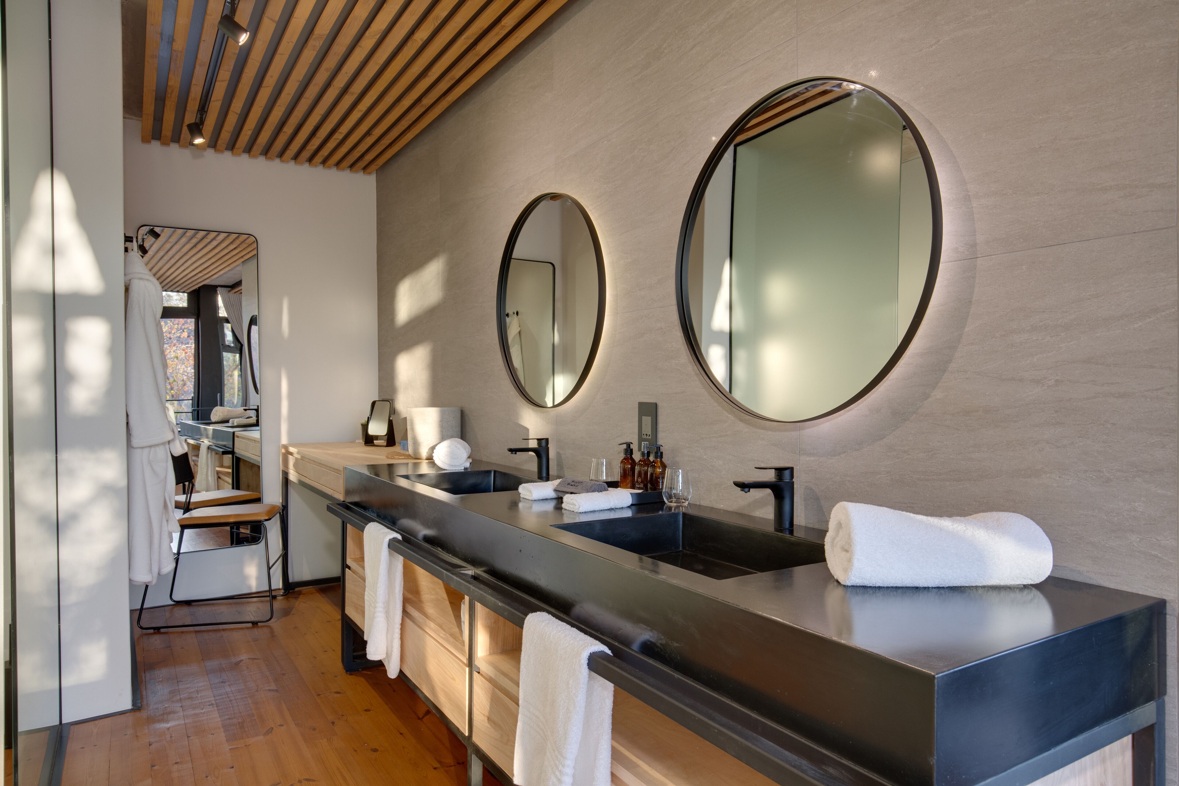 A modern bathroom with a large mirror, a sink, and a towel rack.