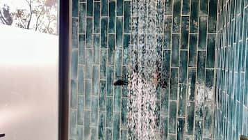 Experience the luxurious shower with a curved showerhead and dark tile walls.