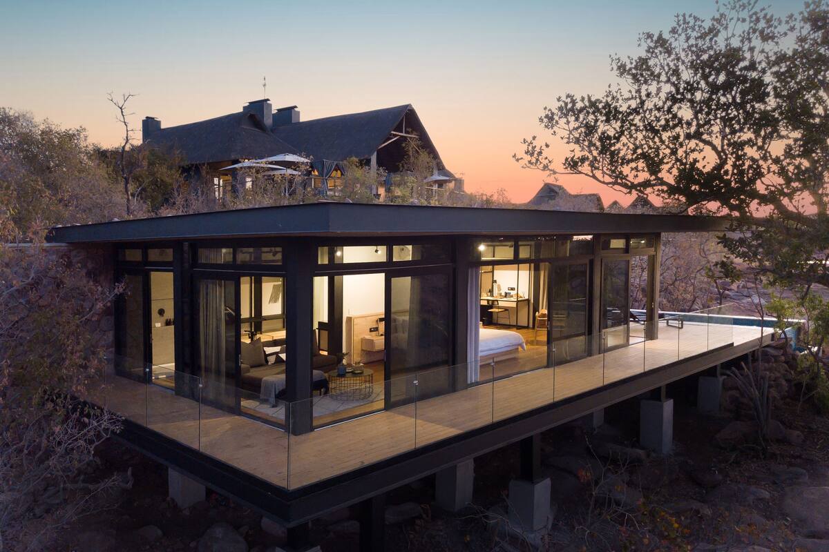 Une maison moderne dotée d’un salon entièrement vitré, d’une chambre et d’un coin repas.