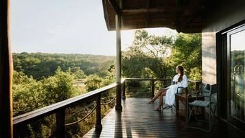 Une terrasse en bois avec un mur de verre donnant sur un paysage boisé.