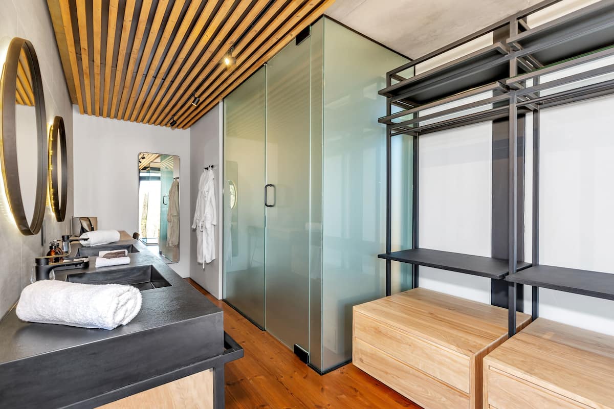 Une salle de bain moderne avec un plafond en bois, une cabine de douche en verre, un lavabo noir et un meuble-lavabo en bois.