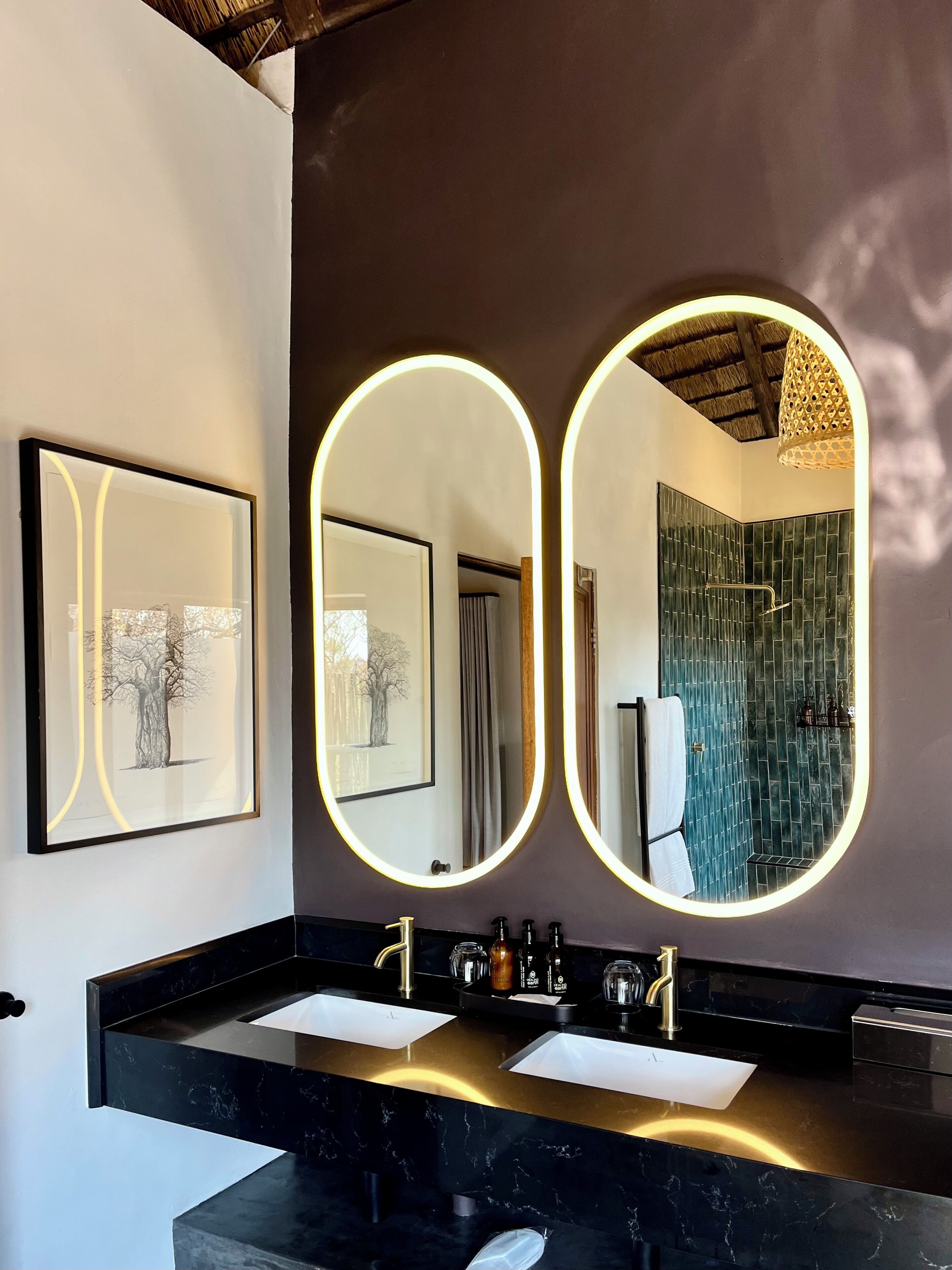 A bathroom with a black marble countertop, two sinks, and three framed pictures.