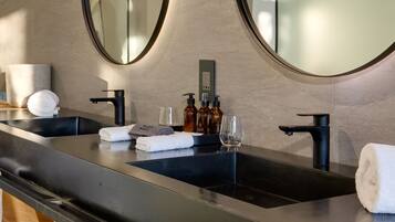 A modern bathroom with two sinks, large mirrors, and a wooden vanity.
