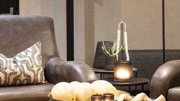 A modern living room with a leather sofa, a round black side table with decorative items, and a floor lamp.