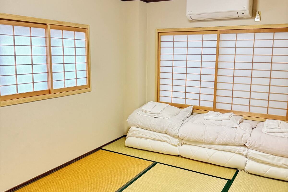 A traditional Japanese room with tatami flooring, a futon bed, and shoji screens.