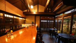 Un espace bar avec un comptoir en bois, des sièges et de grandes fenêtres.