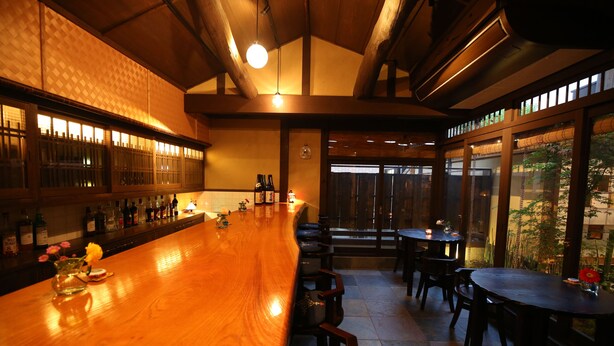 A bar area with wooden bar counter, seating, and large windows. - Ikoi-no-ie (Kyoto)