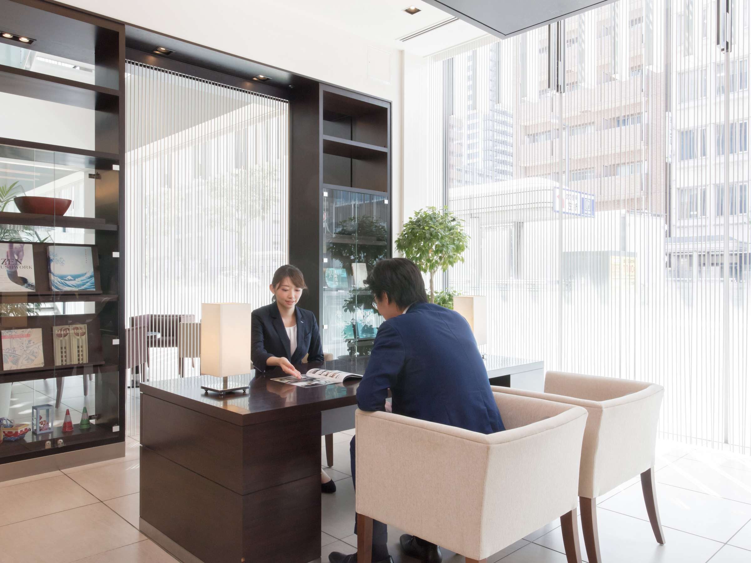 Ein modernes Büro mit Empfangstresen, Bücherregal und großem Fenster mit Blick auf die Stadt.