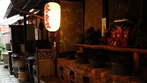A traditional Japanese interior with a wooden table, a hanging lantern, and a brick wall. - Kaikoan (Kyoto)