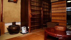 A traditional Japanese room with tatami flooring, a wooden bookshelf, a red lacquered chair, and a traditional Japanese tea set. - Kaikoan (Kyoto)