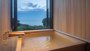 A wooden bathtub with a view of the sea through a large window. - Isaribi (Higashiizu)
