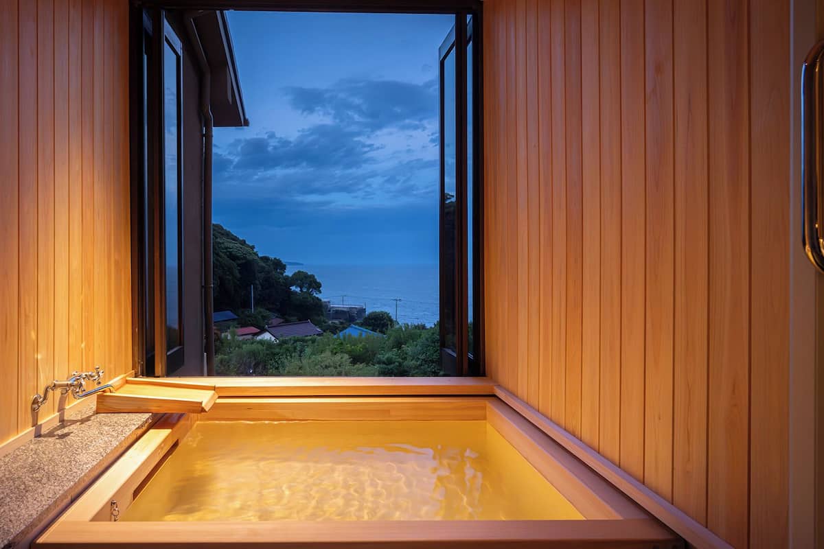A wooden sauna with a view of the sea and houses.