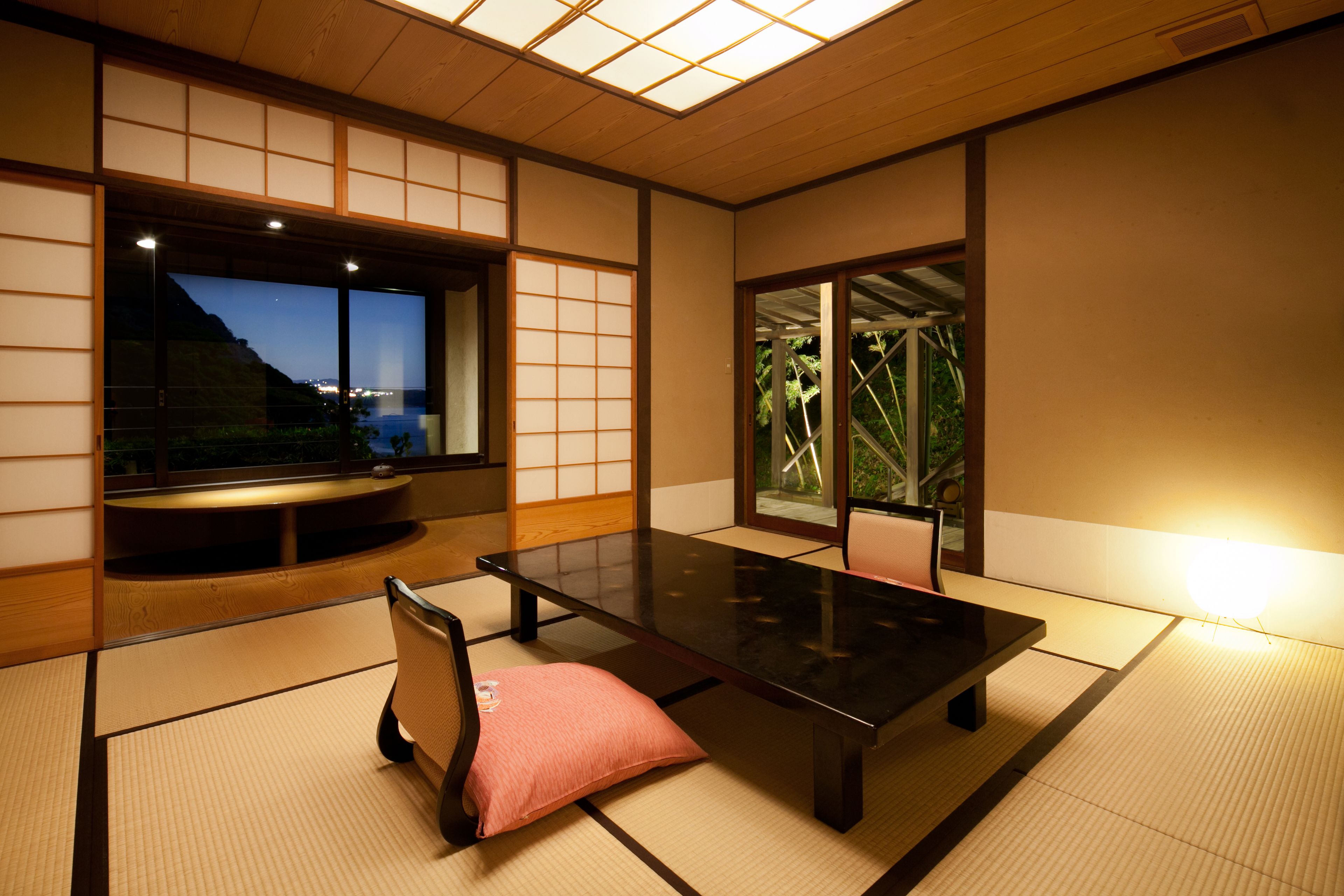 Una habitación japonesa tradicional con suelo de tatami, una mesa baja y puertas correderas.