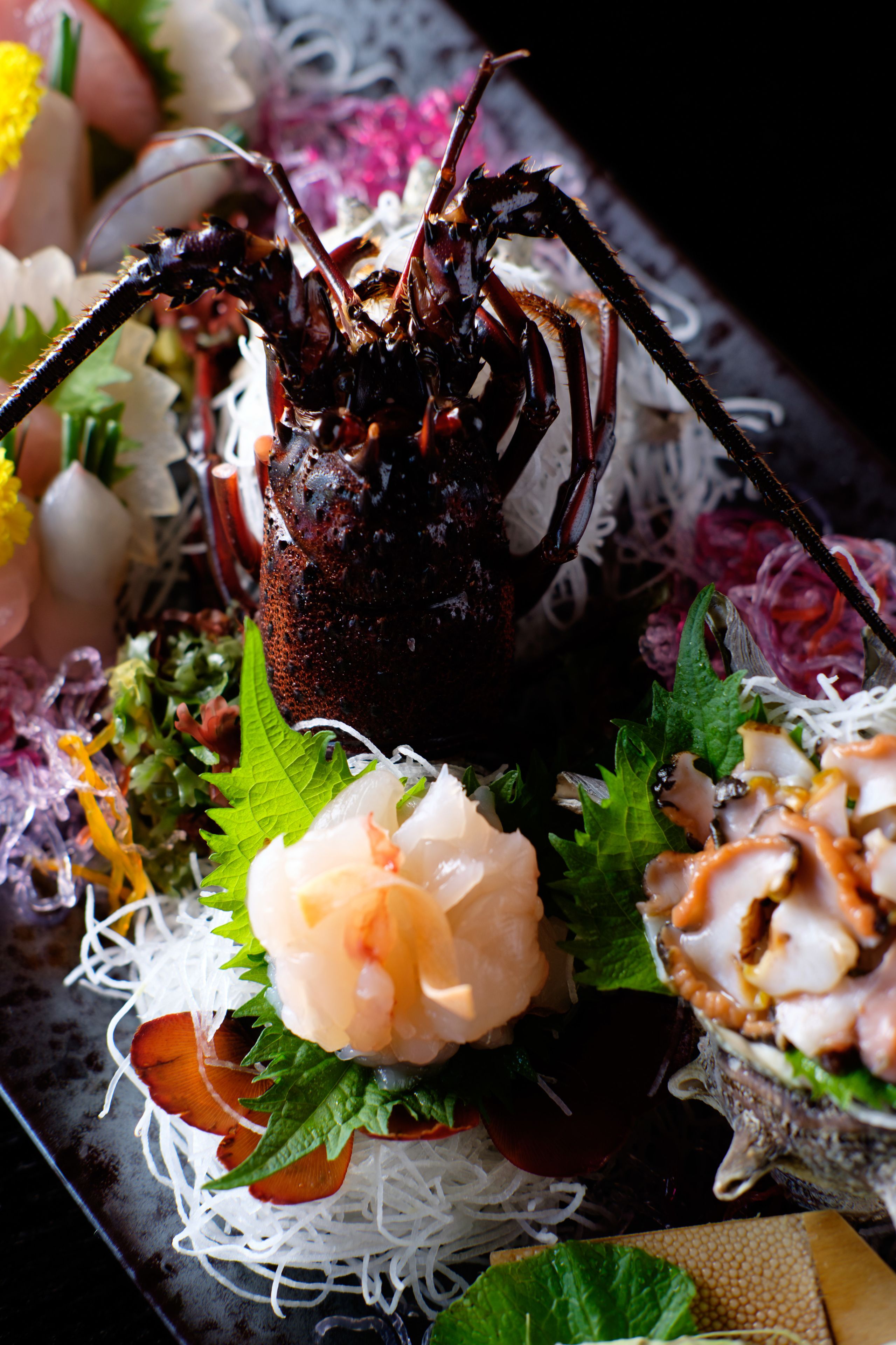 A seafood dish with a lobster centerpiece, garnished with greens and other vegetables.