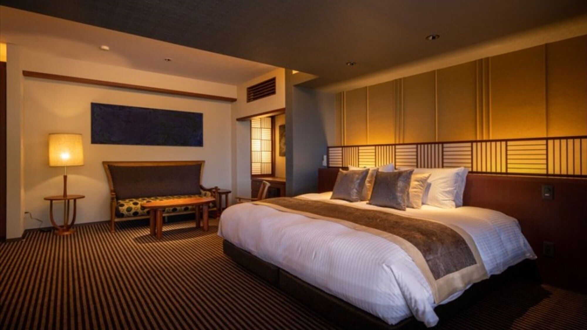 Una habitación de hotel con una cama grande, un sofá, un escritorio y una lámpara.