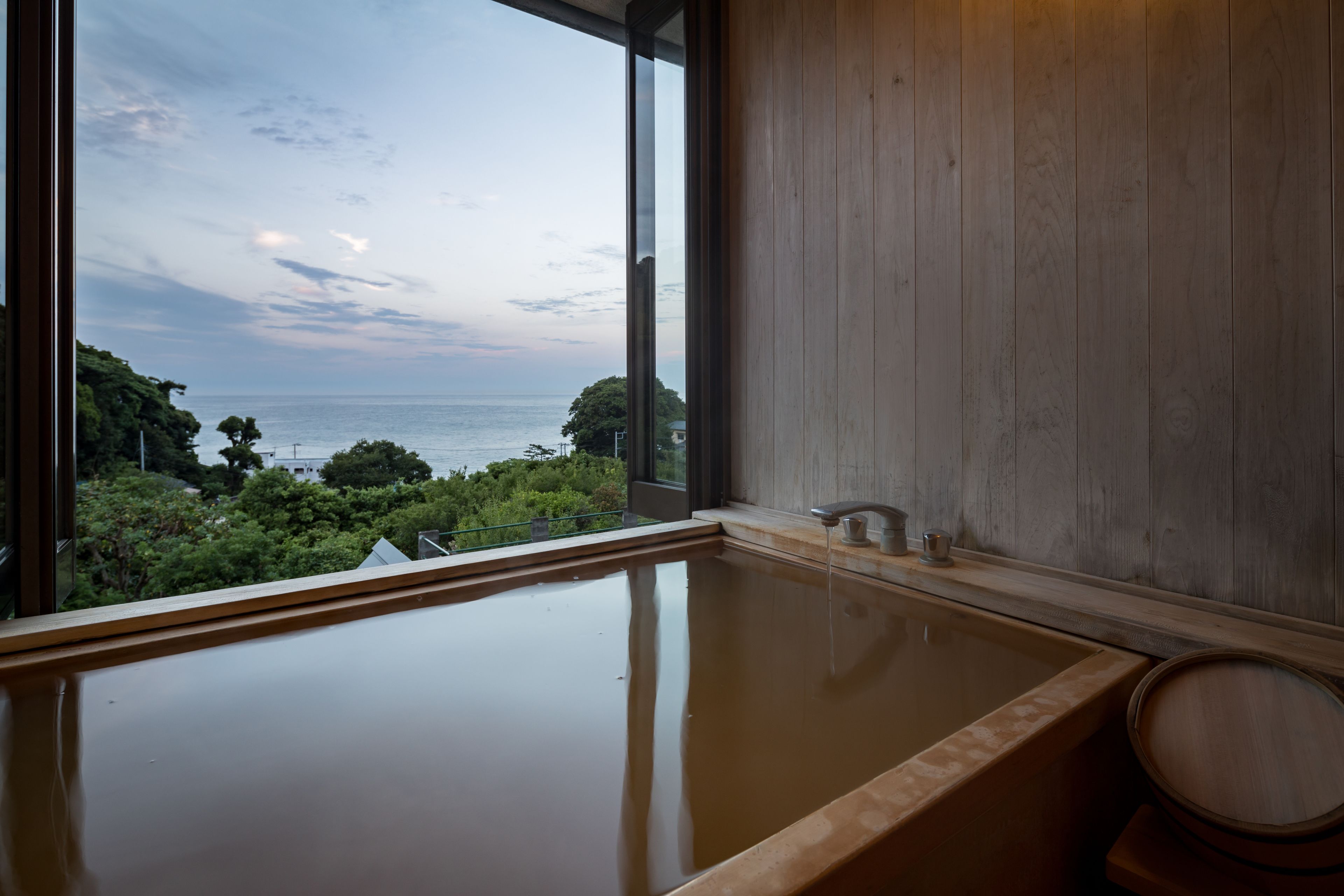 A modern bathroom with a large bathtub and a view of the sea.
