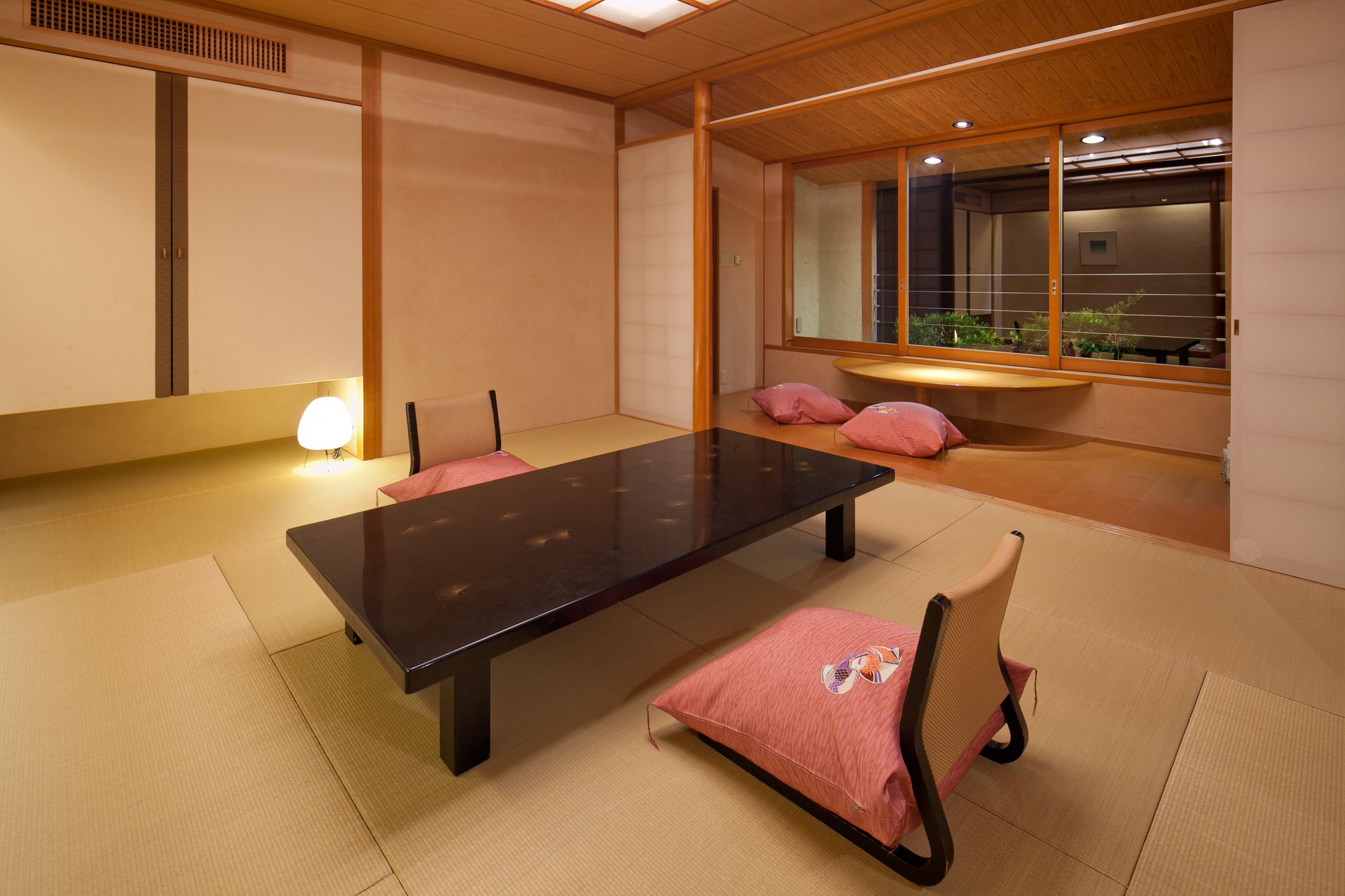 A traditional Japanese-style room with tatami flooring, a low table, and cushions.