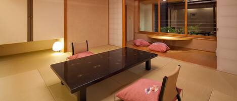 A traditional Japanese-style room with tatami flooring, a low table, and cushions.