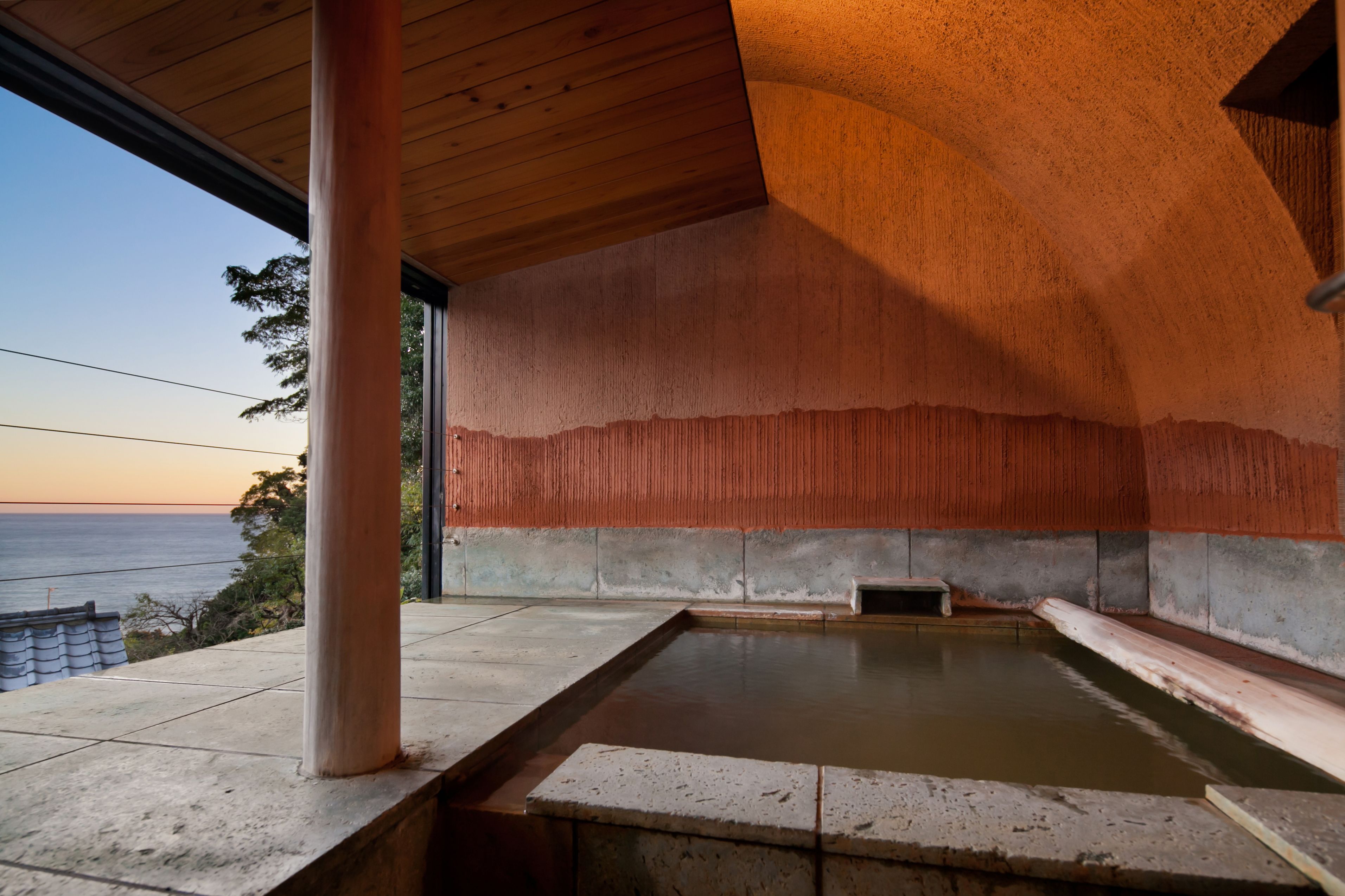A spa area with a large hot tub, a wooden ceiling, and a view of the sea.