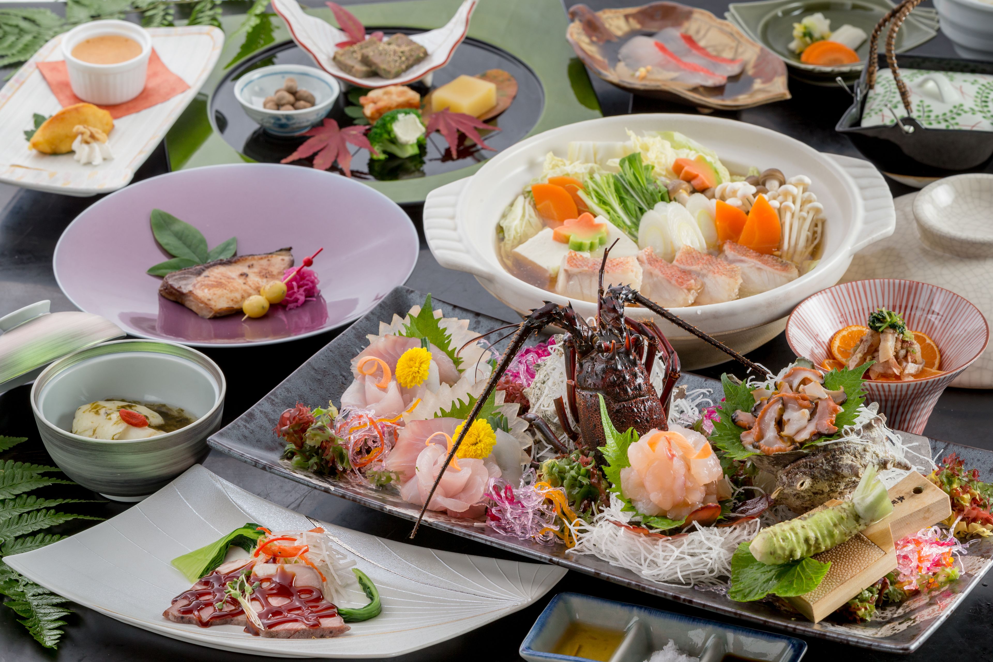 A variety of dishes including seafood, vegetables, and tofu, presented on a table with multiple bowls and plates.