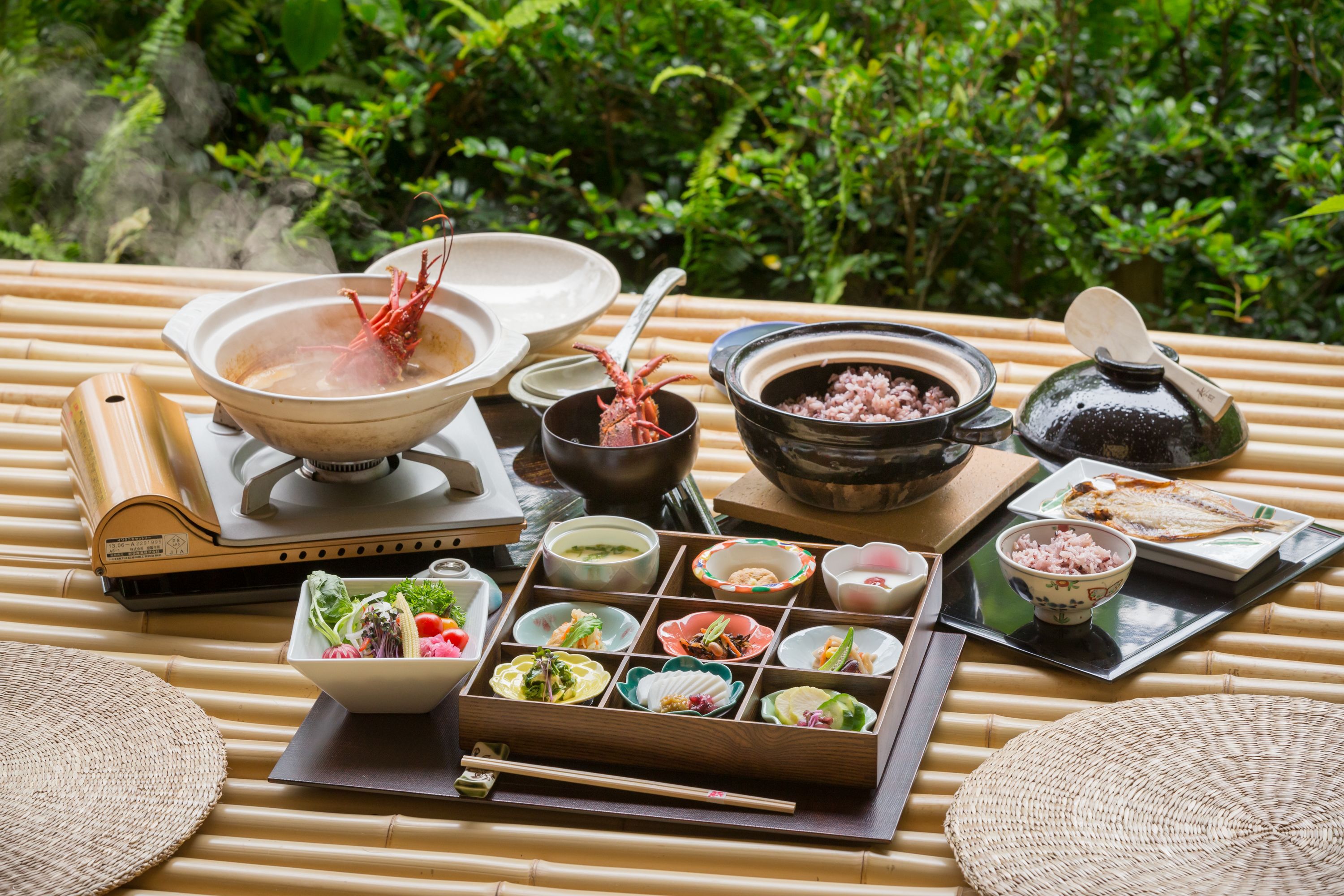 A traditional Japanese meal setup with various dishes and utensils on a bamboo mat.