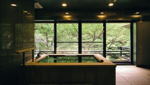 A spa area with a large window, a hot tub, and a wooden bench.