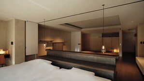 A modern hotel room with a large bed, a small kitchenette, and a bathroom.