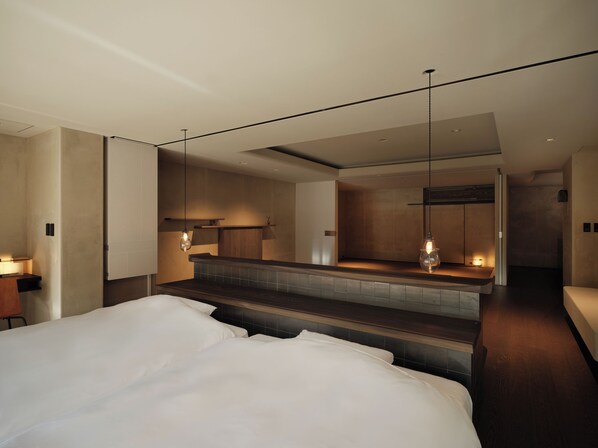 A modern hotel room with a large bed, a small kitchenette, and a bathroom. - Hanamurasaki (Kaga)