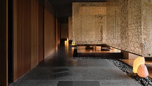 A corridor with a wooden panel wall, a patterned wall, and a bench with a light fixture.