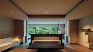 A modern interior with a central seating area, large windows offering a forest view, and a minimalist design.