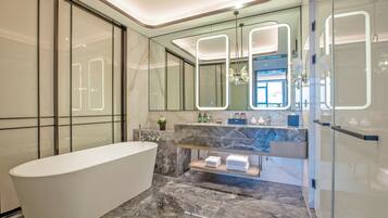 A modern bathroom with a freestanding bathtub, marble countertops, and a glass-enclosed shower area.