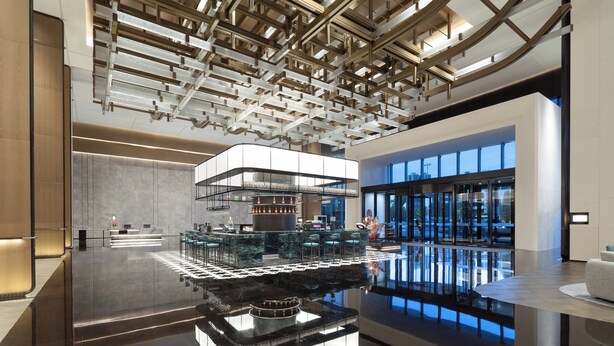 A modern lobby with a central bar area, a reflective floor, and a high ceiling with exposed beams. - Crowne Plaza Huaihua by IHG (Huaihua)