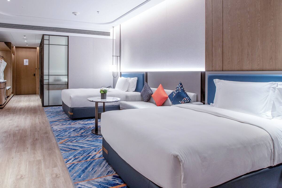 A hotel room with a large bed, a smaller bed, a desk, and a seating area.