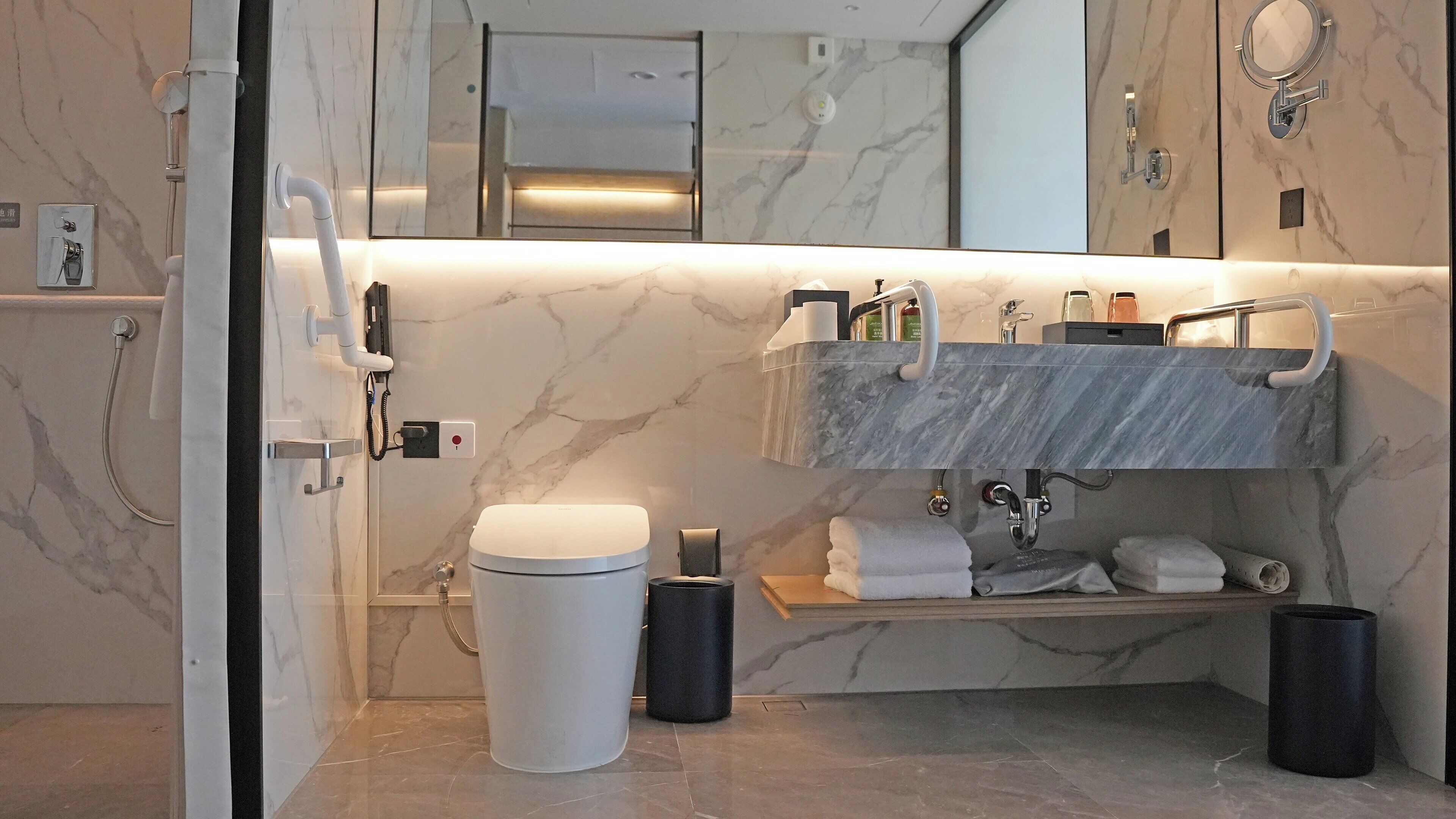 Un baño moderno con salpicadero de mármol, tocador doble, inodoro y zona de ducha.