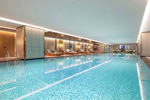 Una amplia piscina interior con sillones de descanso y un diseño moderno.