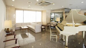A spacious living area with a piano, sofas, and a coffee table. - Hamamatsu Hotel (Hamamatsu)
