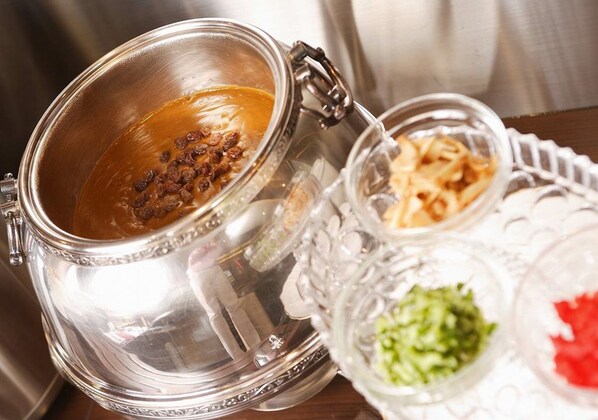 Un recipiente de acero inoxidable con tapa, un tarro de vidrio con asa y un plato de vidrio con alimentos.