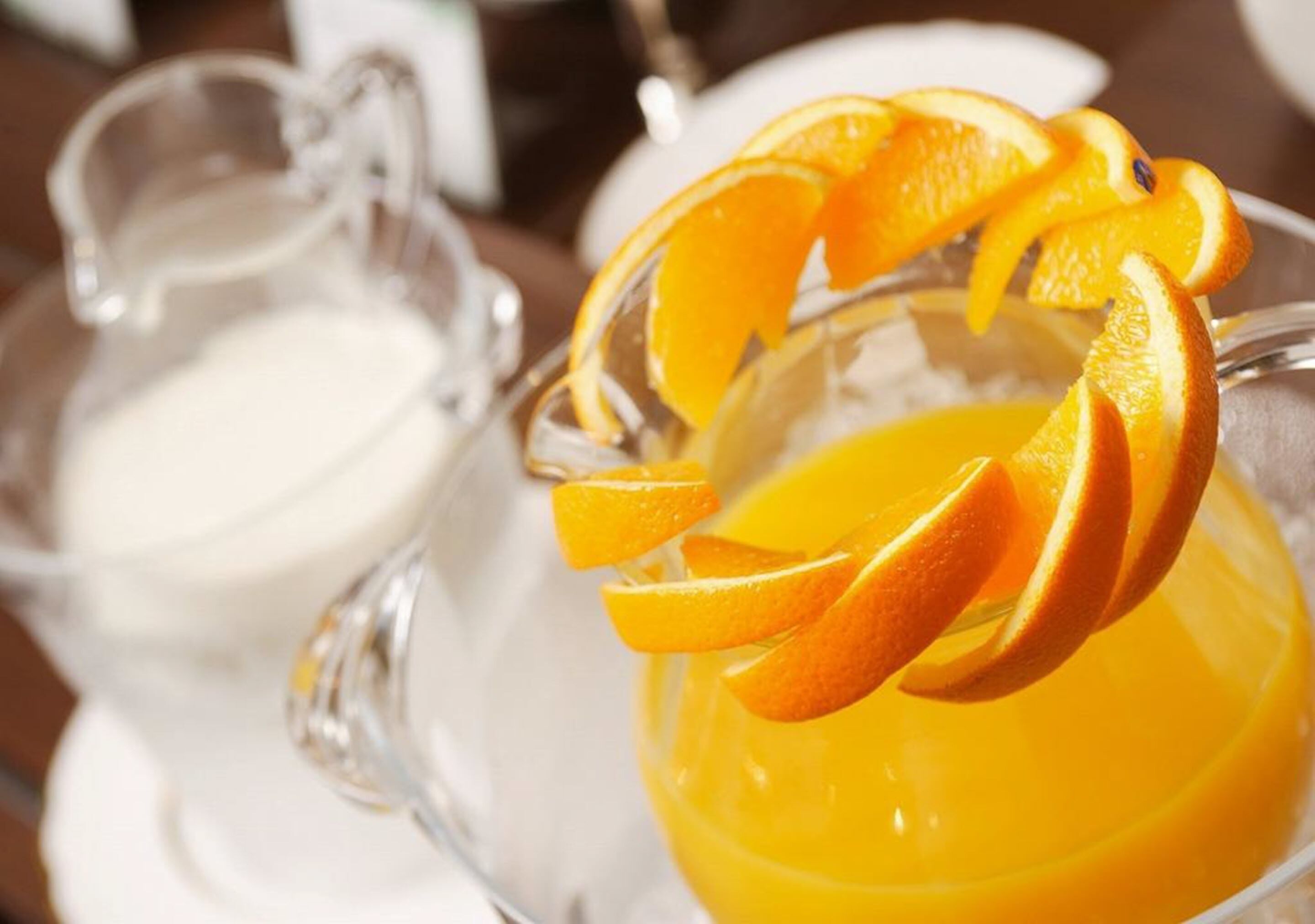 A glass pitcher and a glass with orange slices on a table.