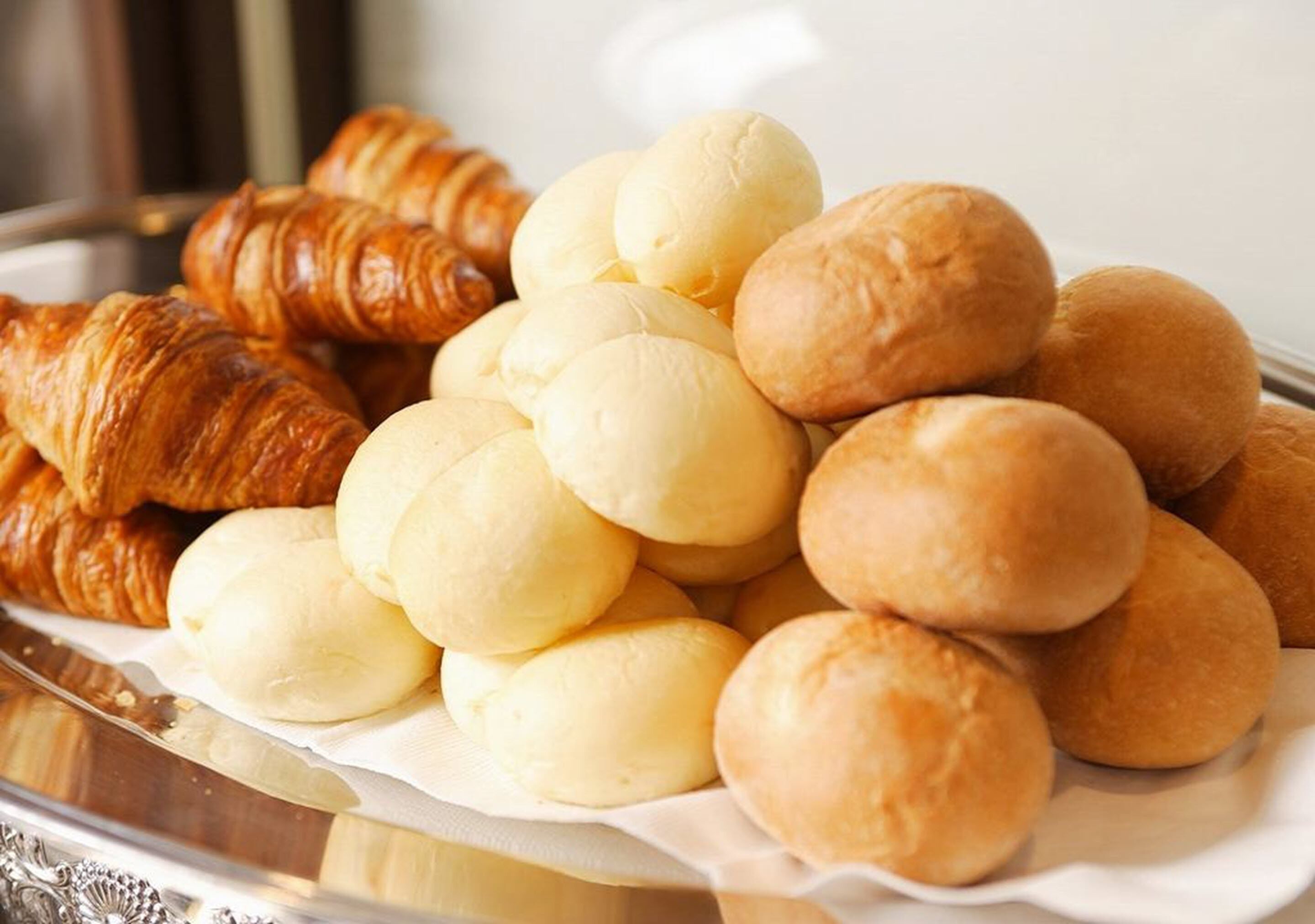 Een dienblad met verschillende gebakjes, waaronder croissants en broodjes.