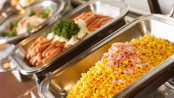 A buffet with various food items including corn, ham, and vegetables.