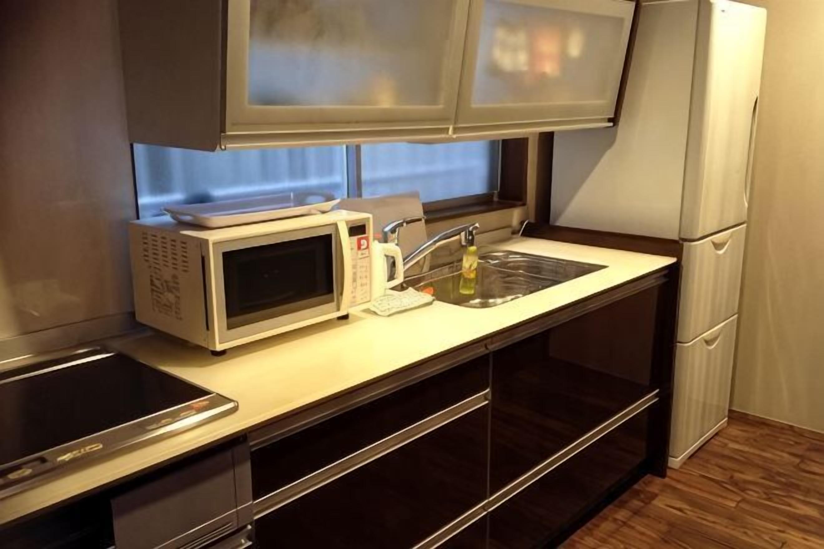 A compact kitchen with a microwave, toaster, sink, and a refrigerator.