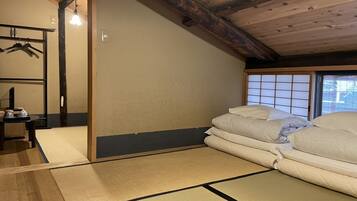 A traditional Japanese room with tatami flooring, a futon bed, a shoji screen, and a hanging clothes rack.