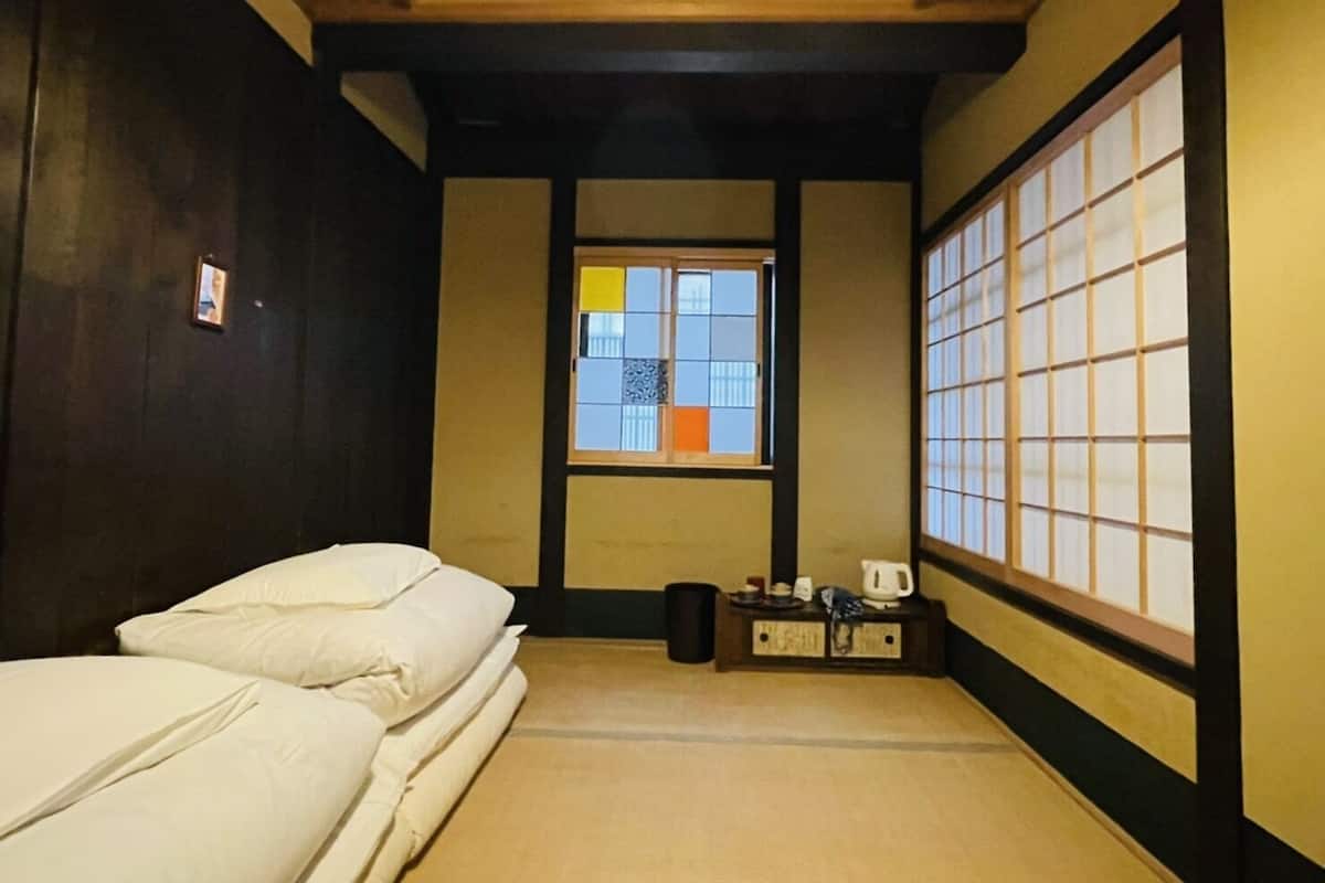 A traditional Japanese room with tatami flooring, a shoji screen, and a futon bed.